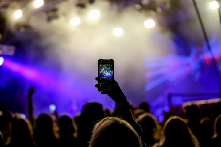 A person taking a photo on their photo at a live music event.